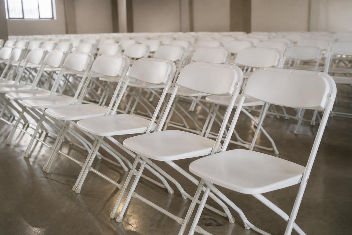 White folding chairs arranged in rows for an indoor event
