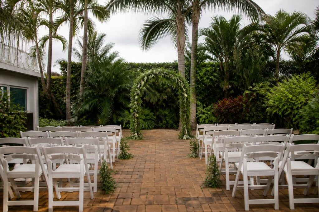 Garden wedding ceremony with white chairs and a central aisle