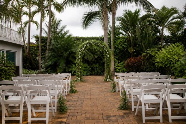 Garden wedding ceremony with white chairs and a central aisle