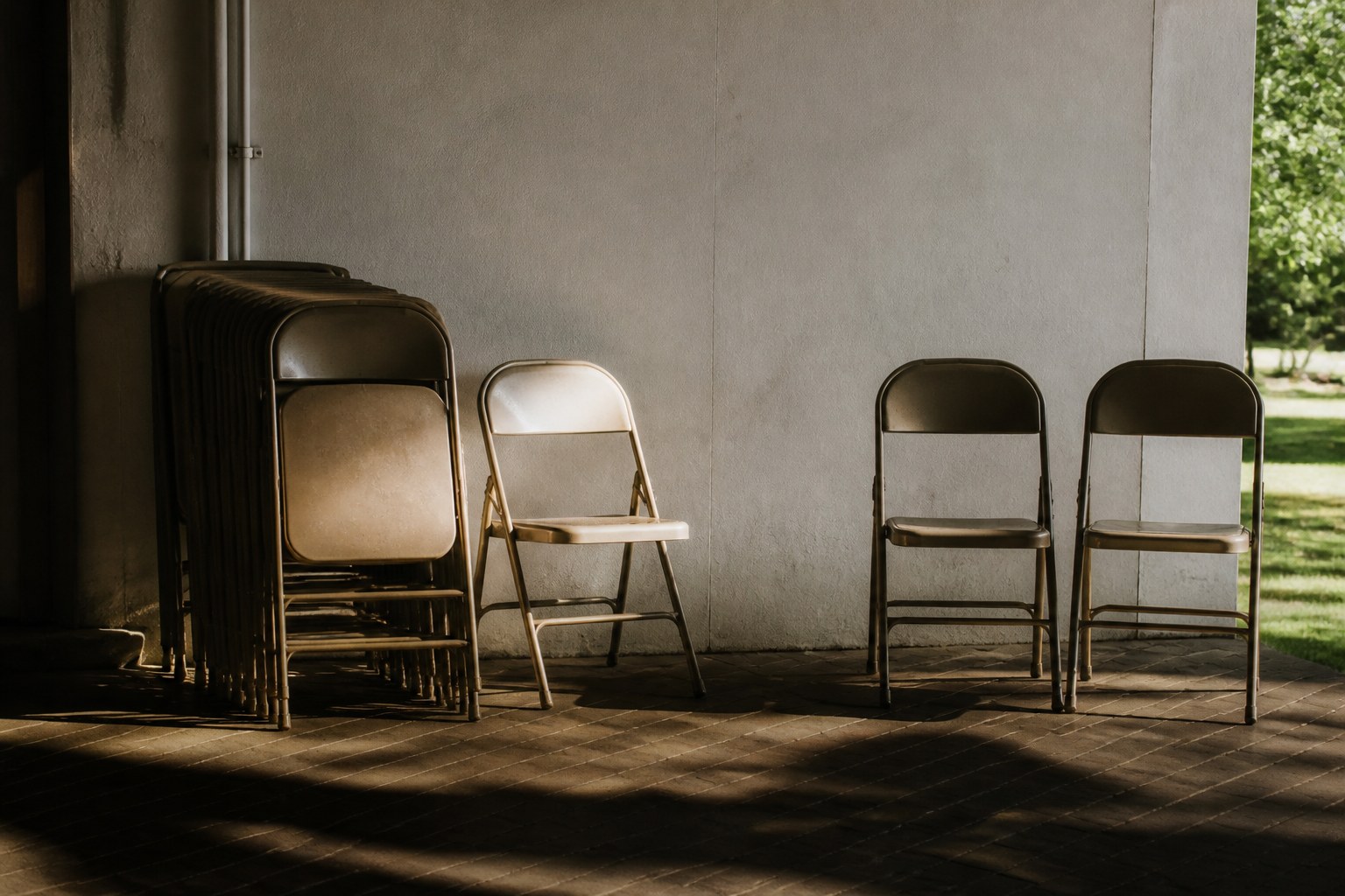 Stack of folding chairs with a few spare chairs set against a wall